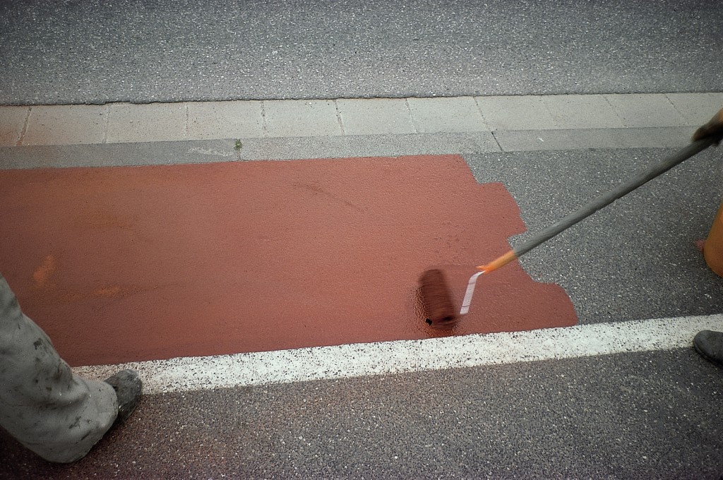 Contractor applies outdoor floor system coating to walkway with stand up roller.