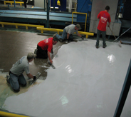 Floor installers work diligently to coat cement.